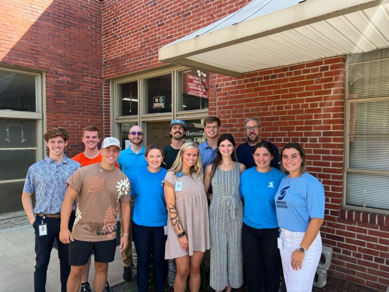 Group of young people in front of a building, smiling.