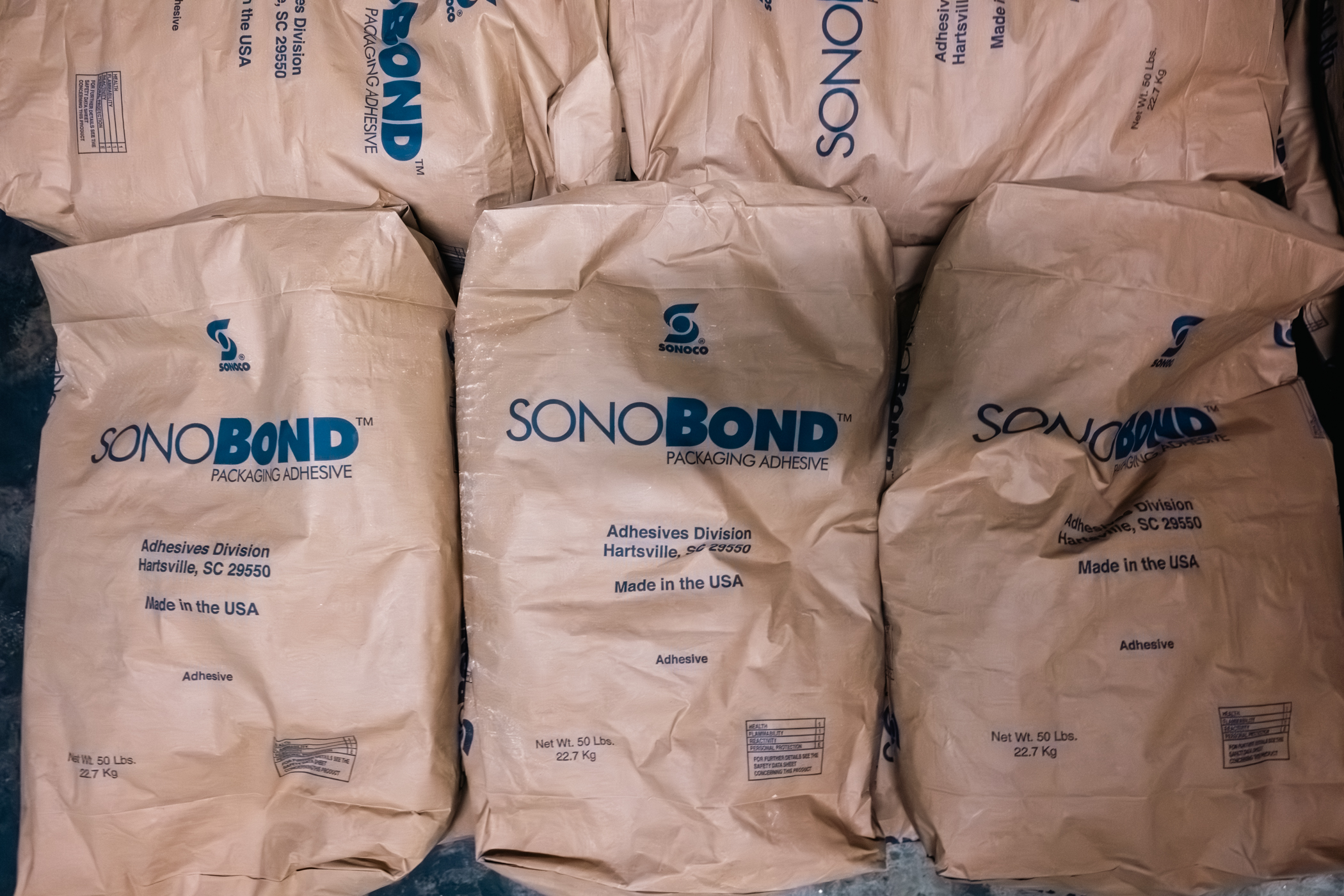 Paper packages labeled SonoBond Packaging Adhesive.