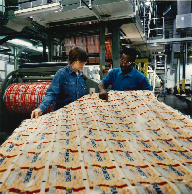 Two employees handling some packaging in a manufacturing environment.
