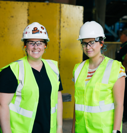 Two people wearing hardhats smiling for a photo