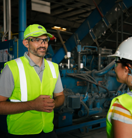 Two people wearing hardhats conversing