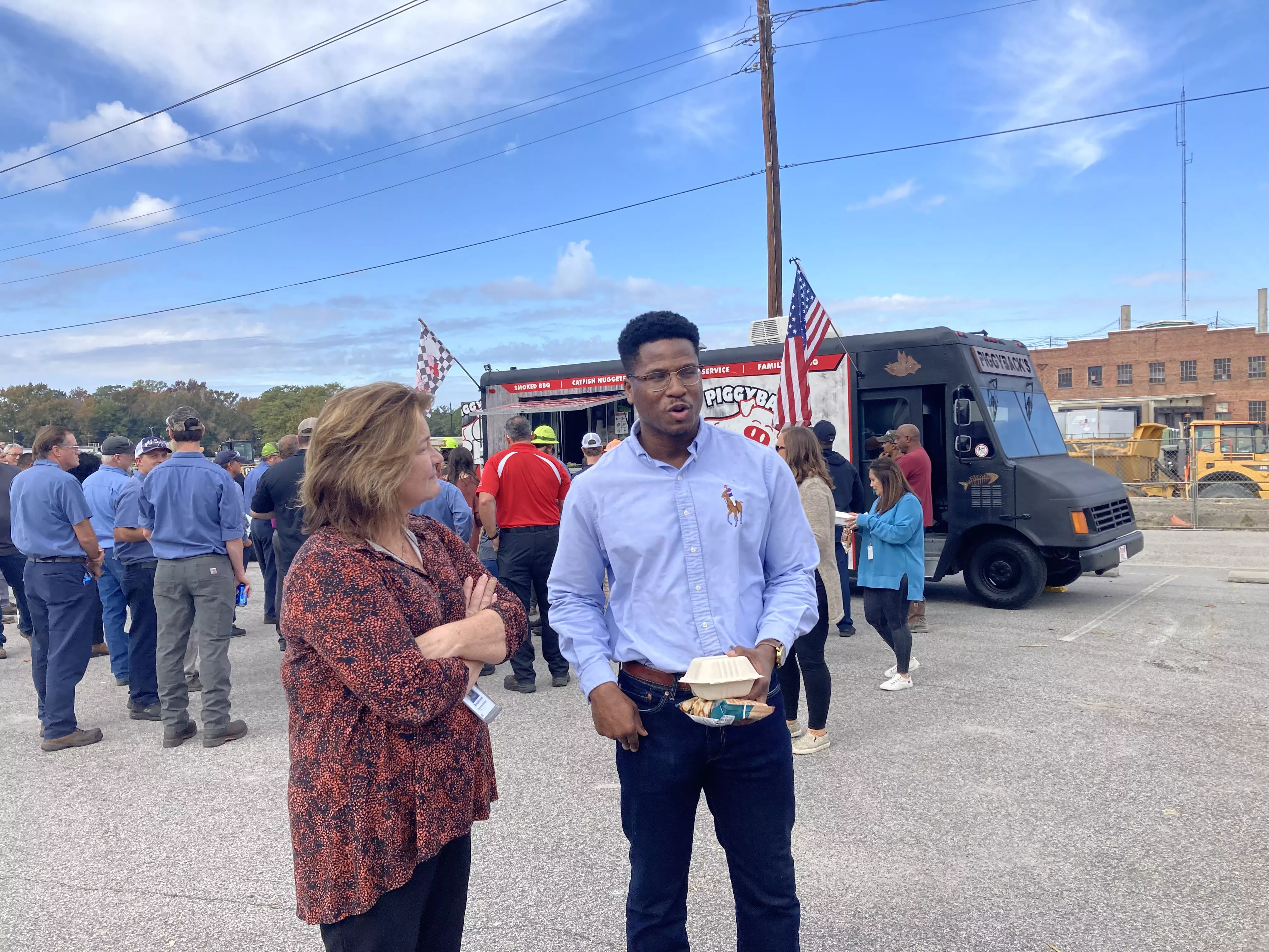 Two coworkers converse at a food truck event.