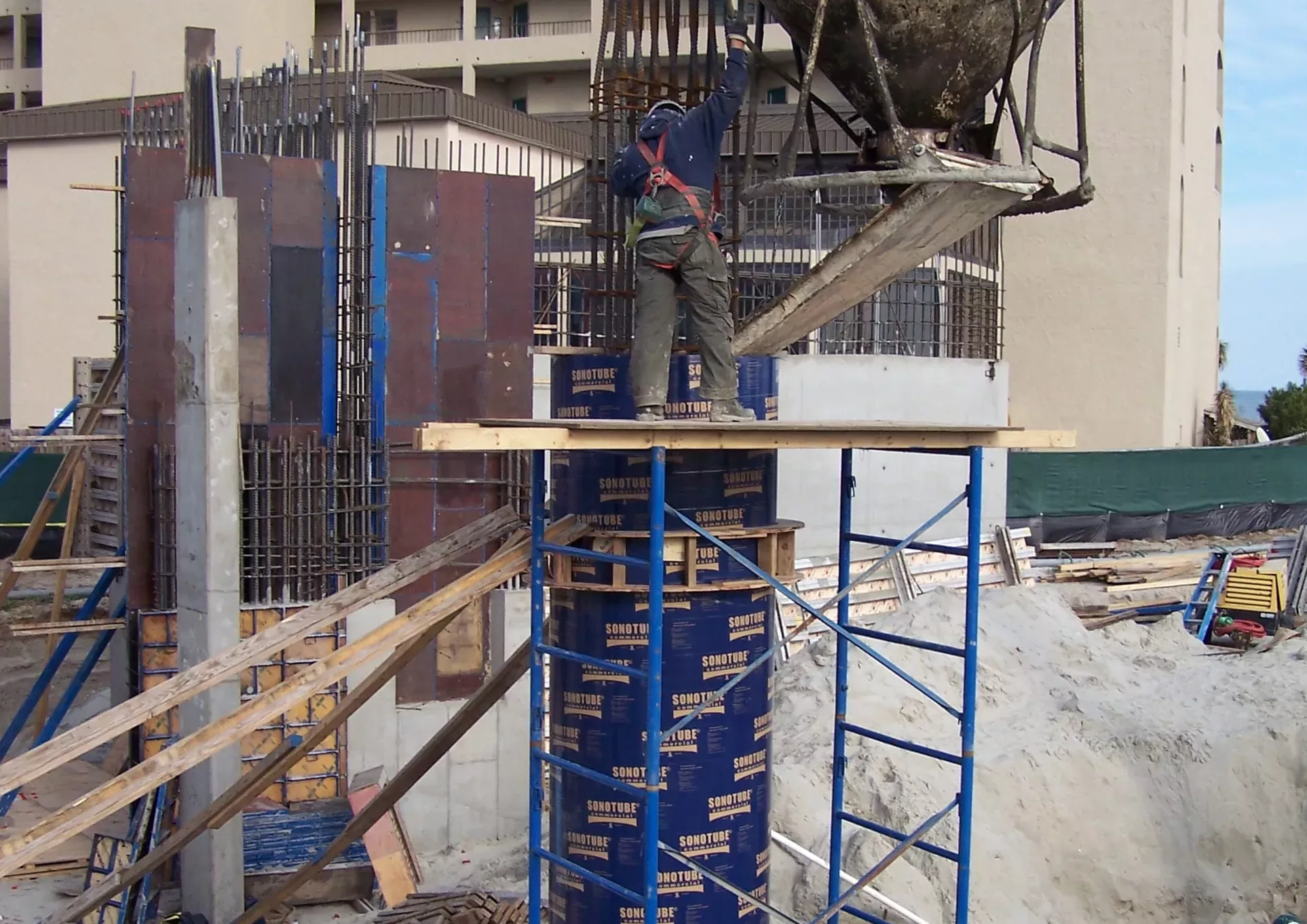 Worker on a platform pours concrete into a Sonotube commercial concrete form