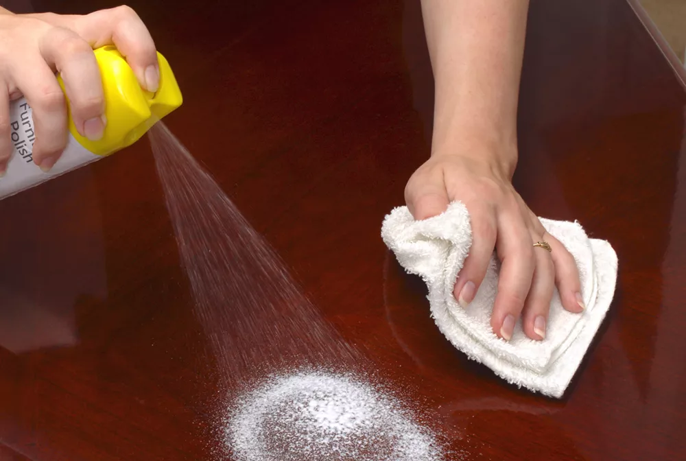 Image of person using aerosol wood cleaner