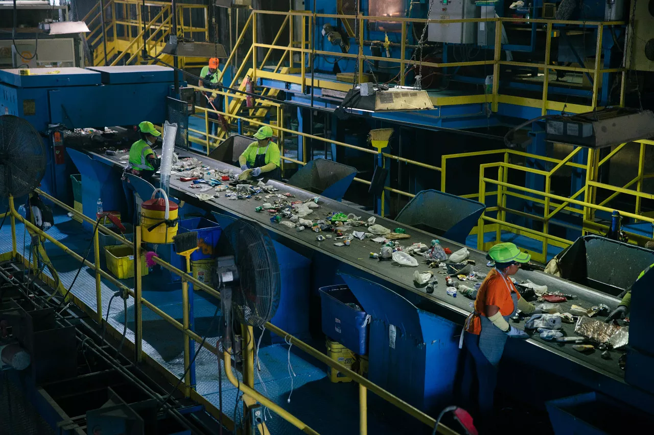 Workers sorting materials in recycling plant.