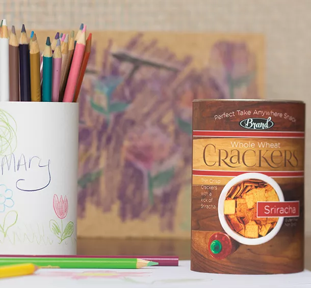 Cracker paper can sitting on a desk next to a paper can being reused for pencils