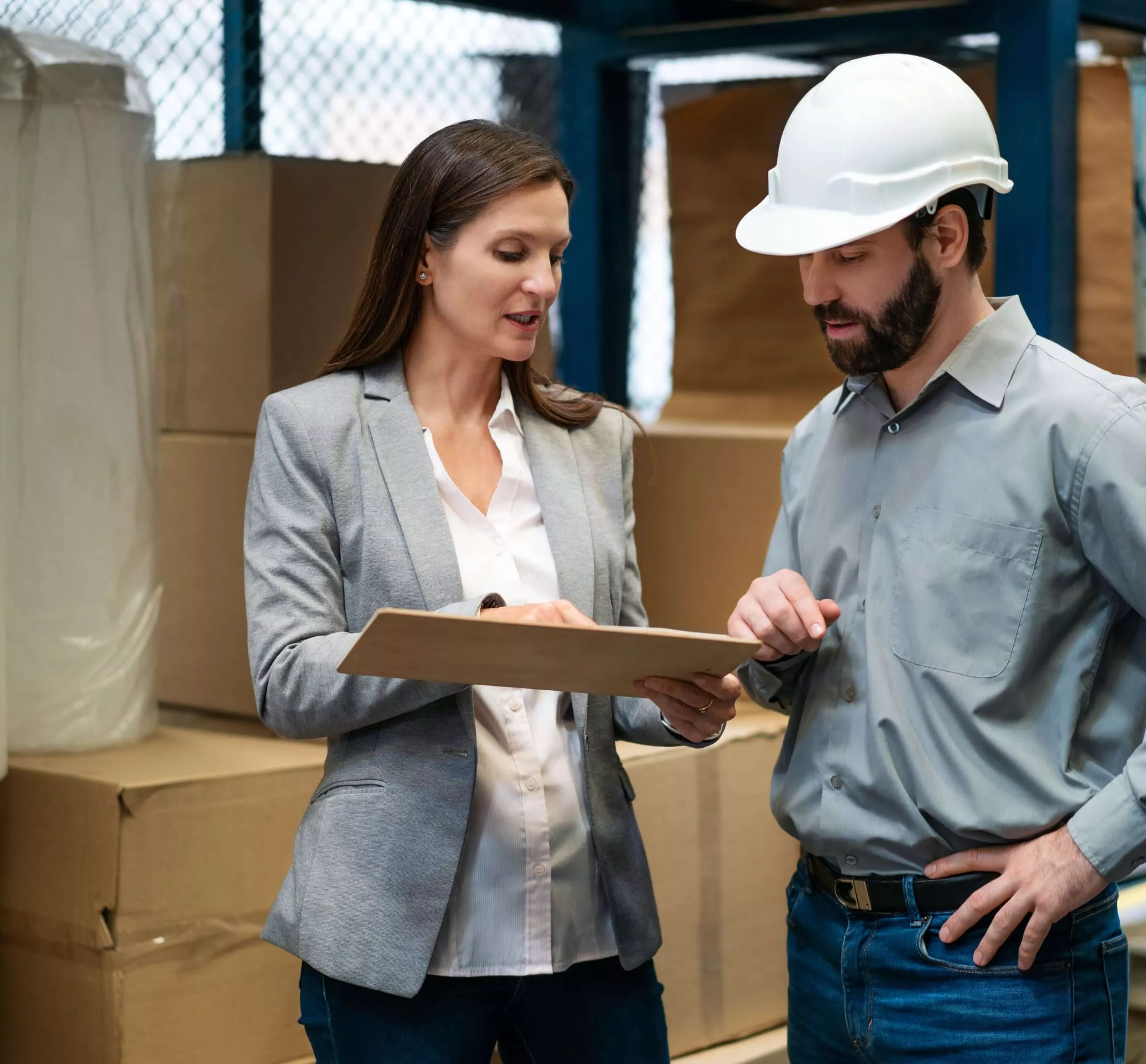 Female manager holding a clipboard and talking with warehouse foreman