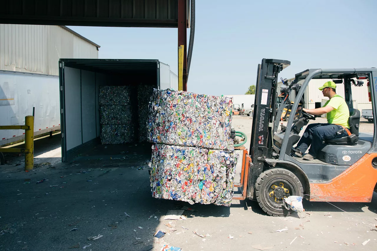 Forklift transporting bales of aluminum cans.