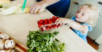 Little girl reaching for grape tomatoes
