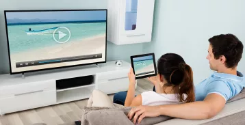 Couple sitting in front of a television, woman on a tablet device