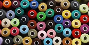 Dozens of spools of thread, of various colors, sitting together