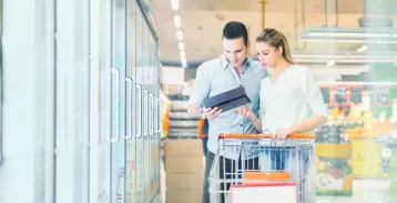 Couple standing in front of the grocery store freezer