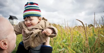 Person holding up toddler in a field