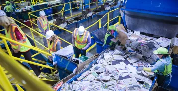 A group of workers beside a pile of paper