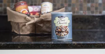 A blue paper container with a clear lid full of chocolate, sitting on a countertop