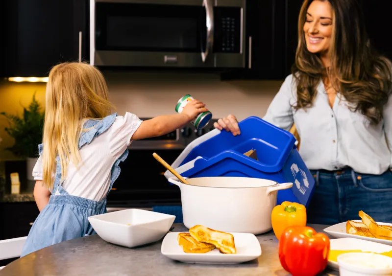 Girl throws a metal can into a recycling bin