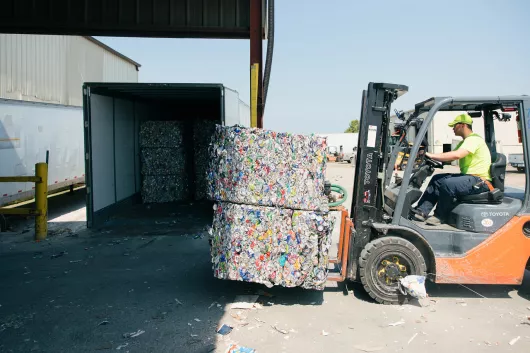 Forklift transporting bales of aluminum cans