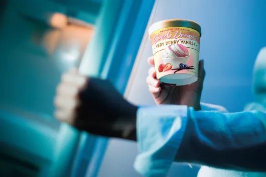 Hand reaching into freezer holding paper ice cream carton