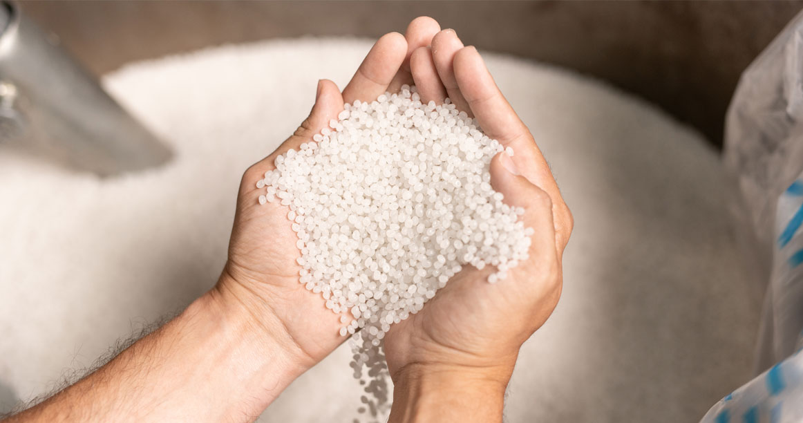 White plastic pellets held in two hands